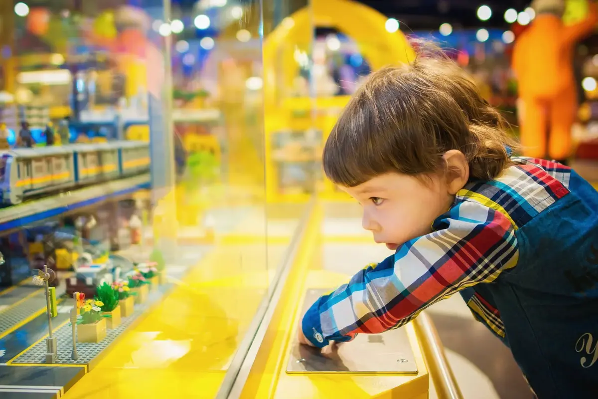 Kilkuletni chłopiec przez szklaną szybę spogląda na małe zabawki