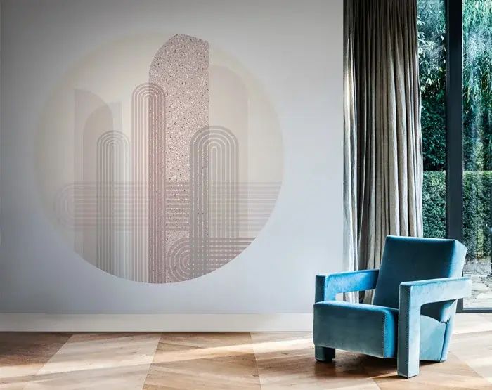 Sciana z minimalistyczną tapetą ścienna w geometryczny wzór, z ustawionym przed niebieskim małym fotelem