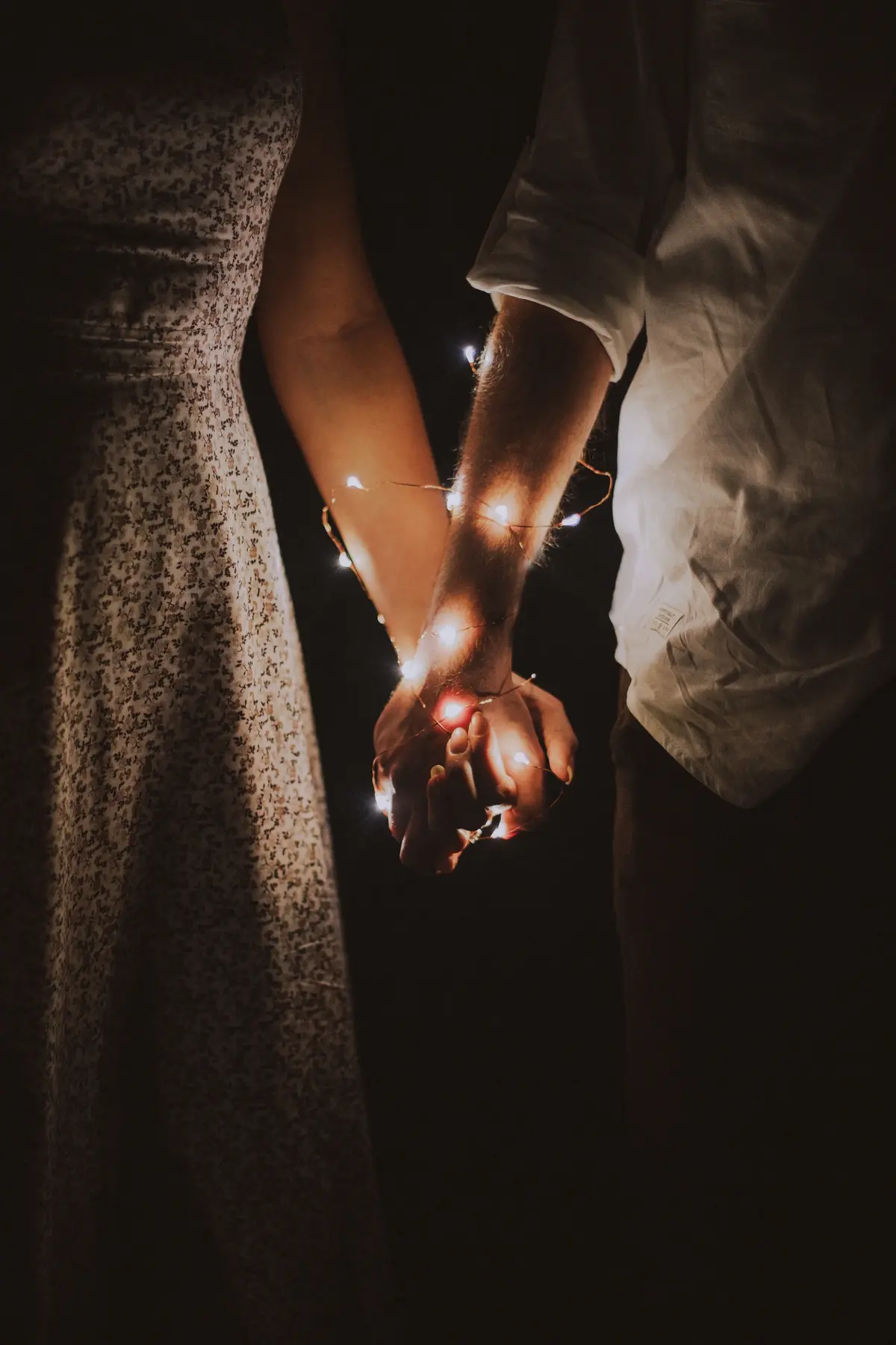 Kobieta i mężczyzna trzymają się za ręce, wokół nich są lampki choinkowe