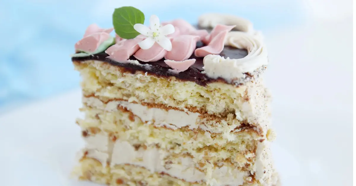 tort przekładany kremem orzechowym z polewą czekoldową i różowo białymi ozdobami 