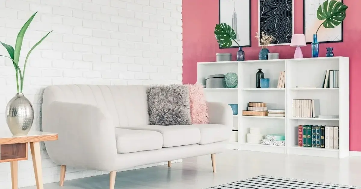 Salon z szara kanapą, jedną ścianą białą, drugą różową