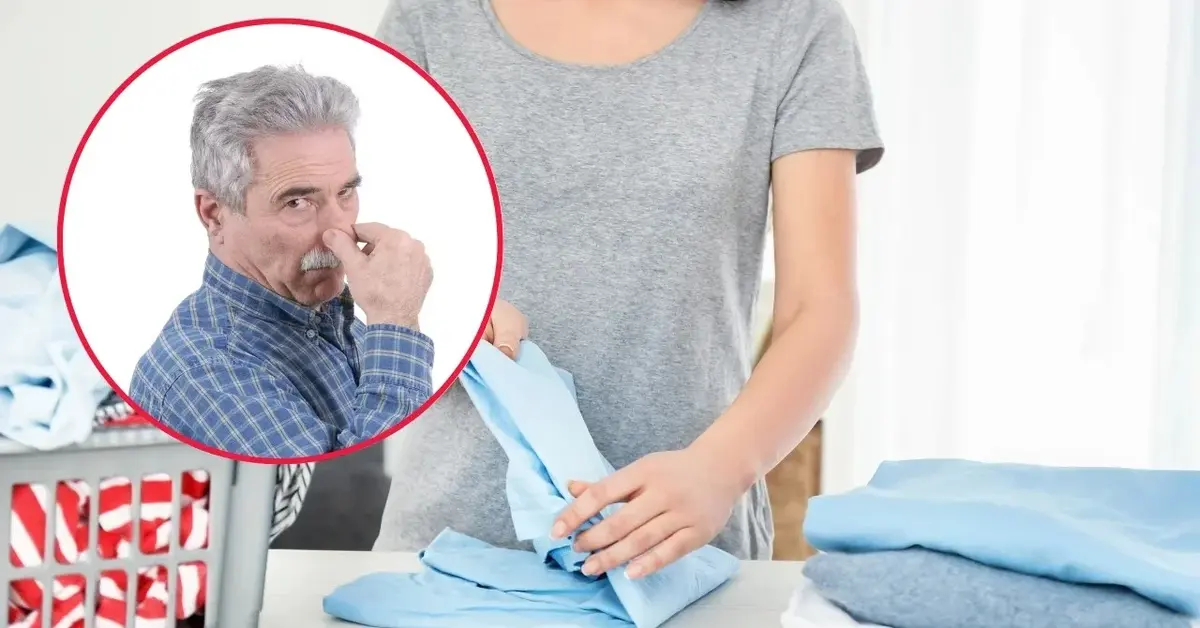 Mężczyzna zatyka nos, bo kobieta składa ubrania, które śmierdzą po praniu.