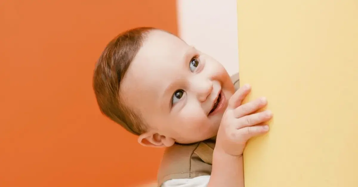 Uśmiechnięte dziecko przy pomarańczowej i żółtej ścianie