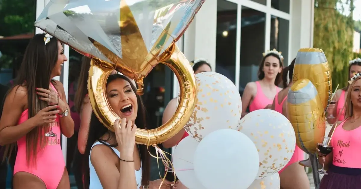 Uśmiechnięte dziewczyny z nadmuchanymi balonami bawią się na wieczorze panieńskim.