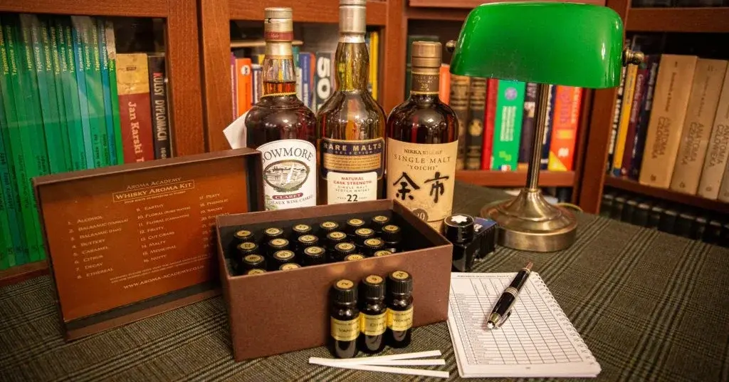 Zestaw próbek do analizy i degustacji whisky w ciemnym drewnianym gabinecie na biurku z zieloną lampą