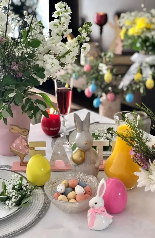 Kolorowe jajka i kwiaty na wielkanocnym stole.