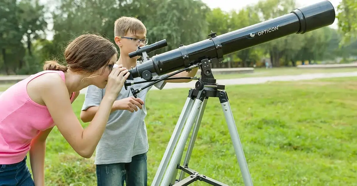 Dwójka dzieci używa teleskopu w piękny wiosenny dzień