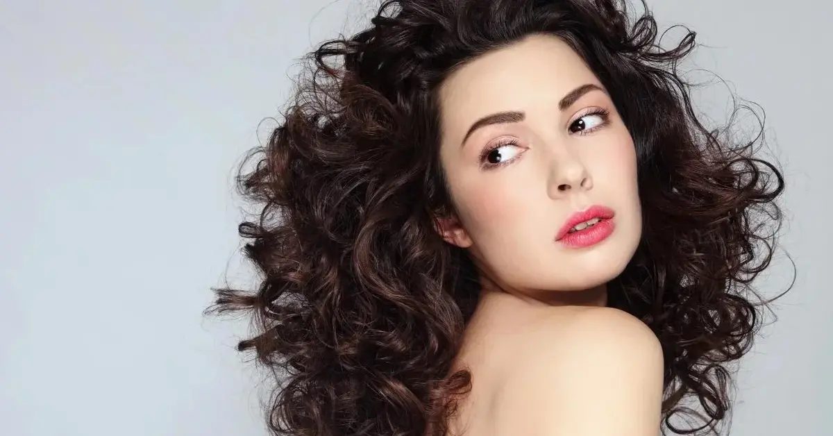 Kobieta z kręconymi włosami. Jej loki błyszczą od oleju z pestek malin.