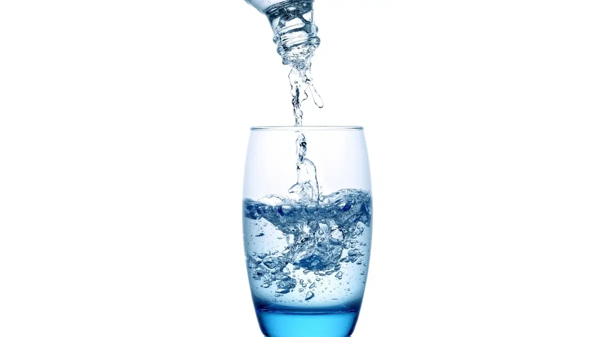Woda jest przelewna z butelki do szklanki.