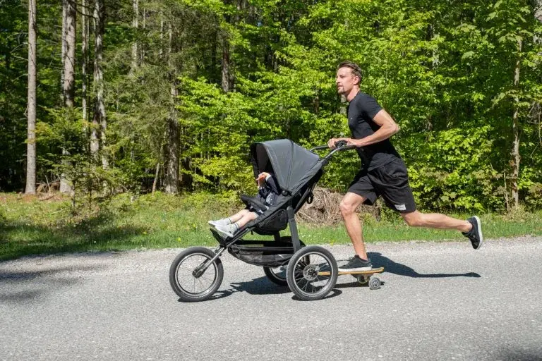 W lesie mężczyzna w trakcie joggingu z wózkiem sportowym do biegania dla dziecka