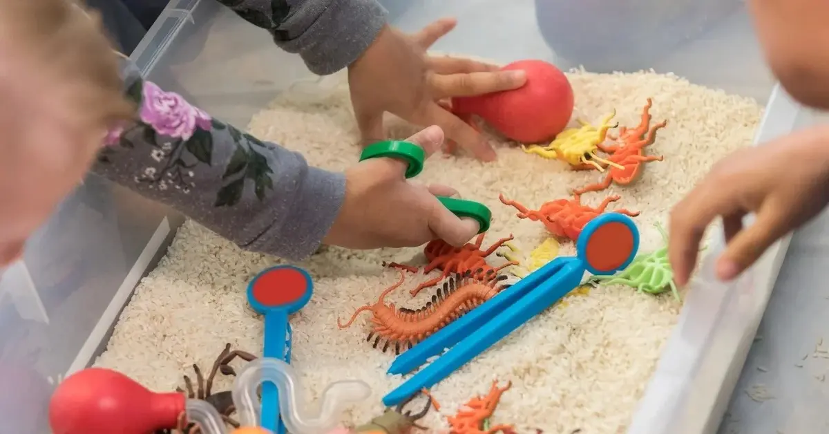 zabawa sensoryczna dla dzieci piasek figurki o różnych kształtach i kolorach