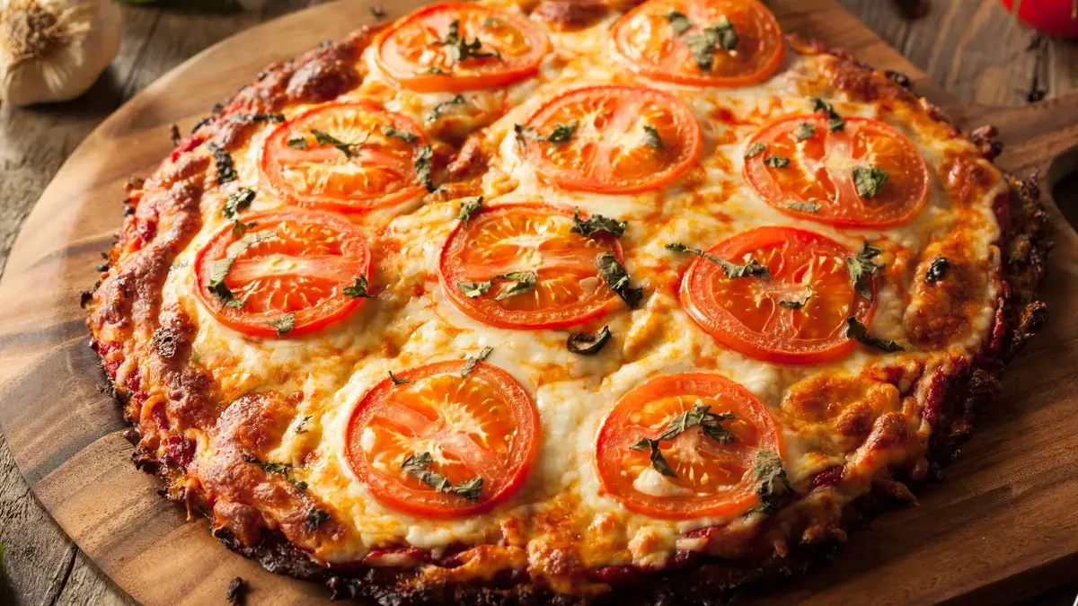 Pizza z kalafiora  pomidorami na drewnianej desce 