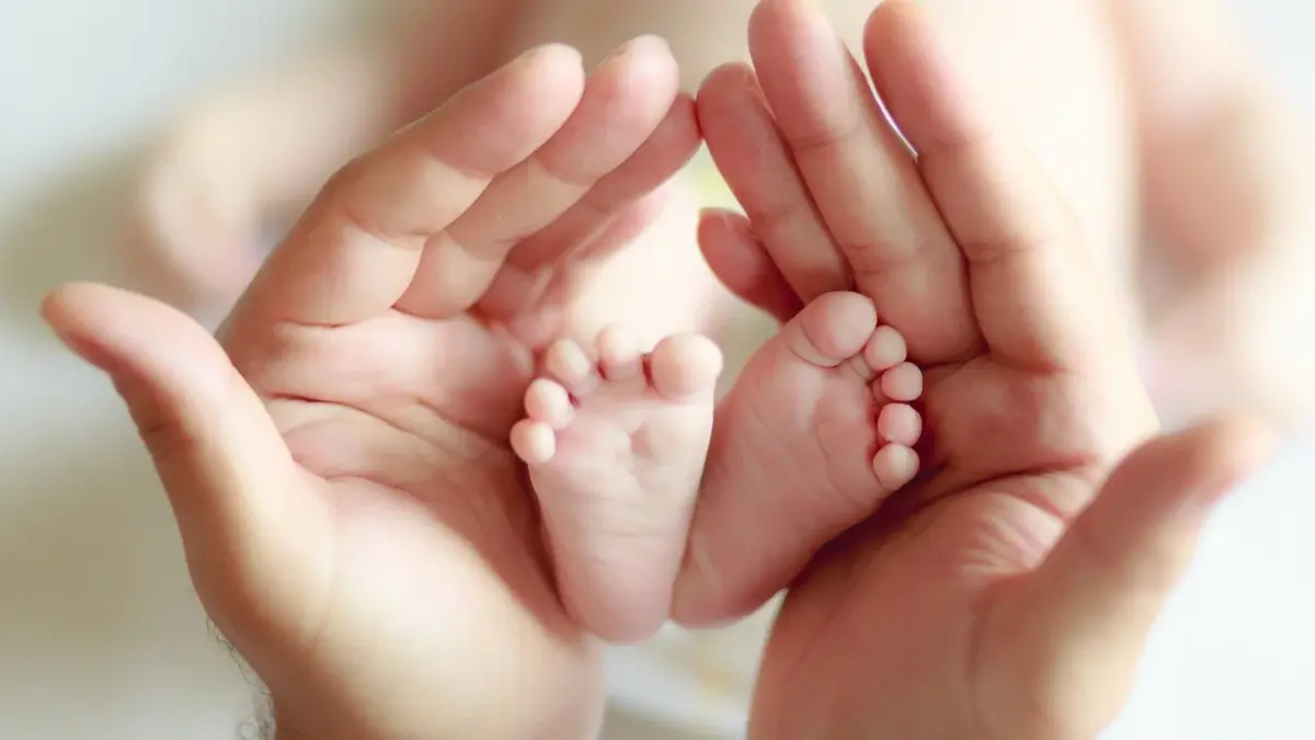Stópki noworodka trzymane w dłoniach mamy