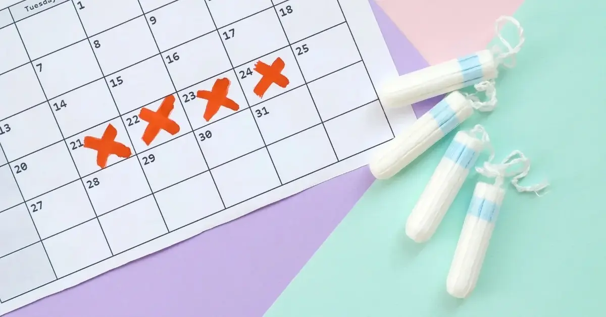 Kalendarz z zaznaczonymi krzyżykami dni miesiaczki, obok tampony