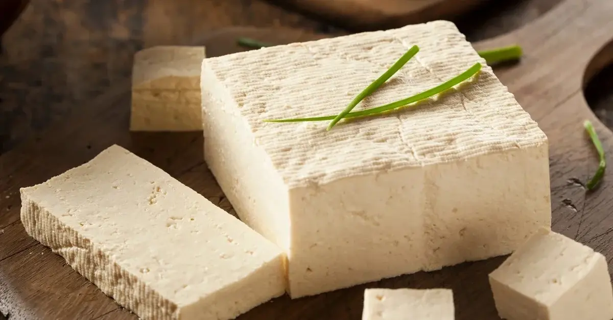 tofu w kostce z ukrojonym plastrem na drewnianej desce
