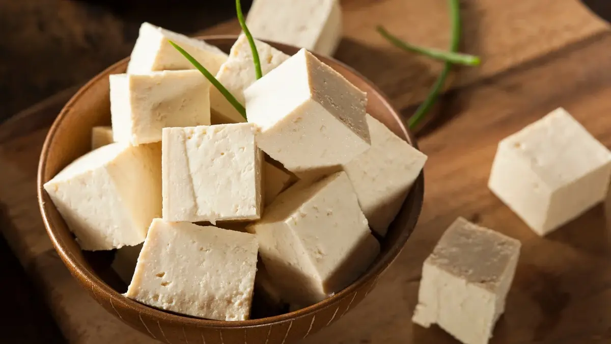 tofu w kosteczkach w miseczce na drewnianym blacie 