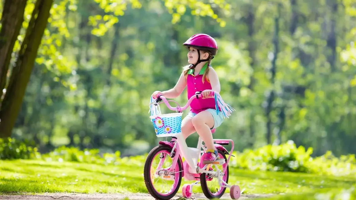 Dziewczynka jadąca na różowym rowerze w lesie