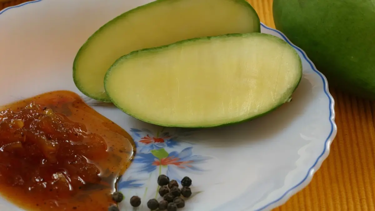 Chutney z mango na talerzu, obok świeże mango