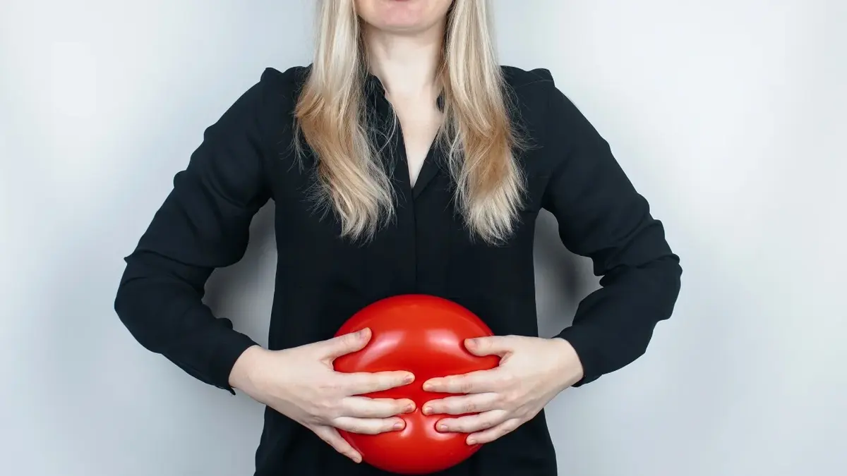 Kobieta ściskająca przed sobą czerwony balonik