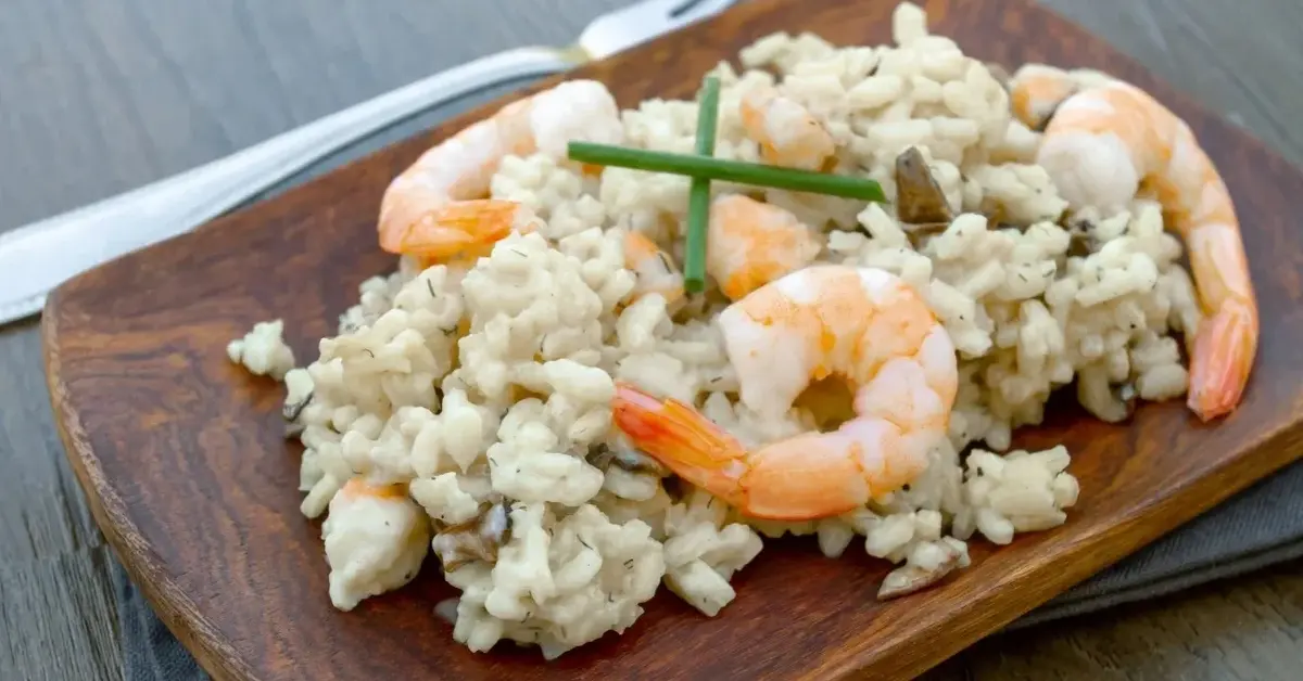 Risotto z krewetkami na drewnianym, prostokątnym talerzu