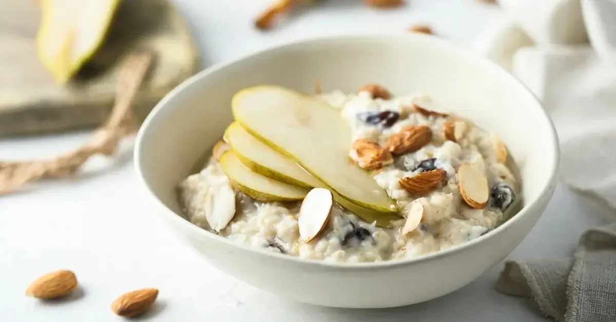 Owsianka na mleku w białej miseczce z gruszkami, migdałami