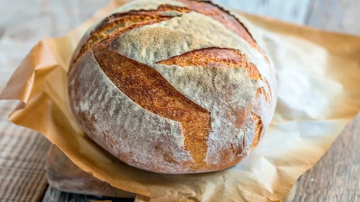 Okrągły wypieczony bochenek chleba na papierze do pieczenia