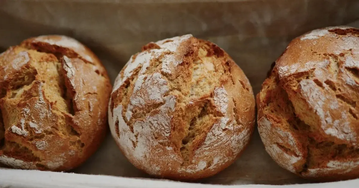 Trzy świeże bochenki chleba oparte o ścianę
