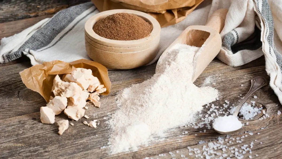 Składniki potrzebne do przygotowania chleba: mąka, drożdże, sól na drewnianym blacie