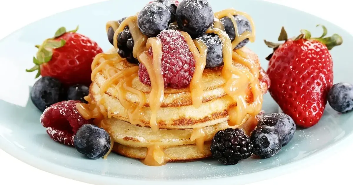 Racuchy ułożone w wieżyczkę z owocami na białym talerzu