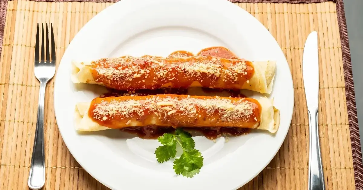 Naleśniki z wytrawnym farszem polane sosem na białym talerzu