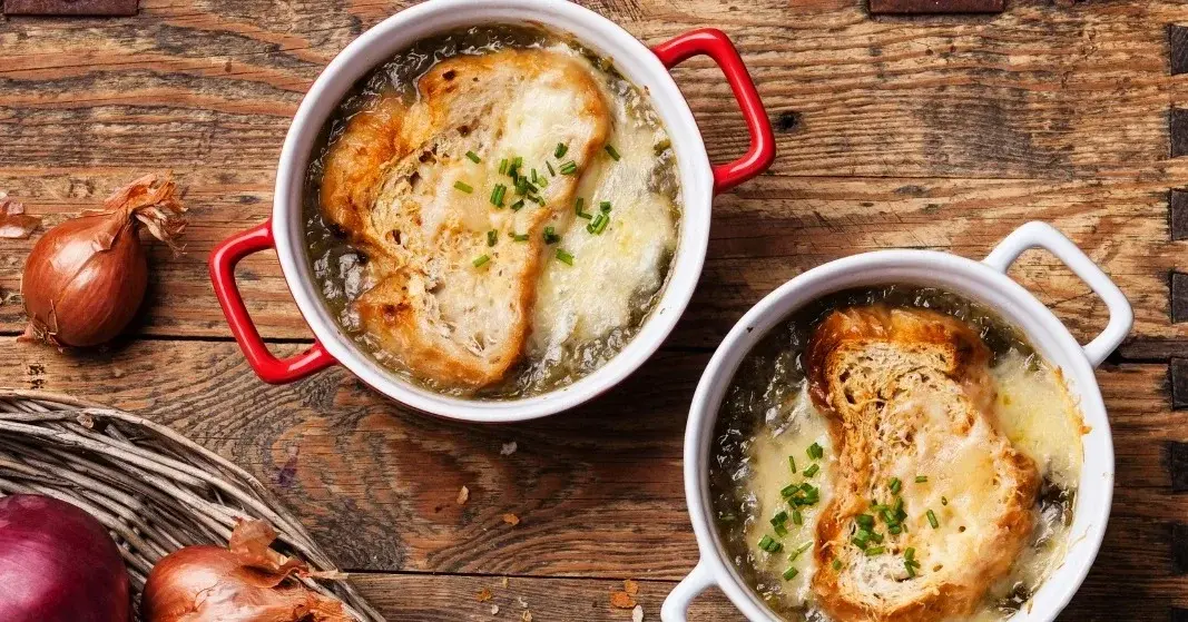 Zupa cebulowa w dwóch małych miseczkach z uszkami z zapieczonymi grzankami z serem na wierzchu