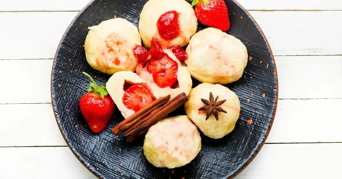 Knedle z truskawkami na czarnym talerzu