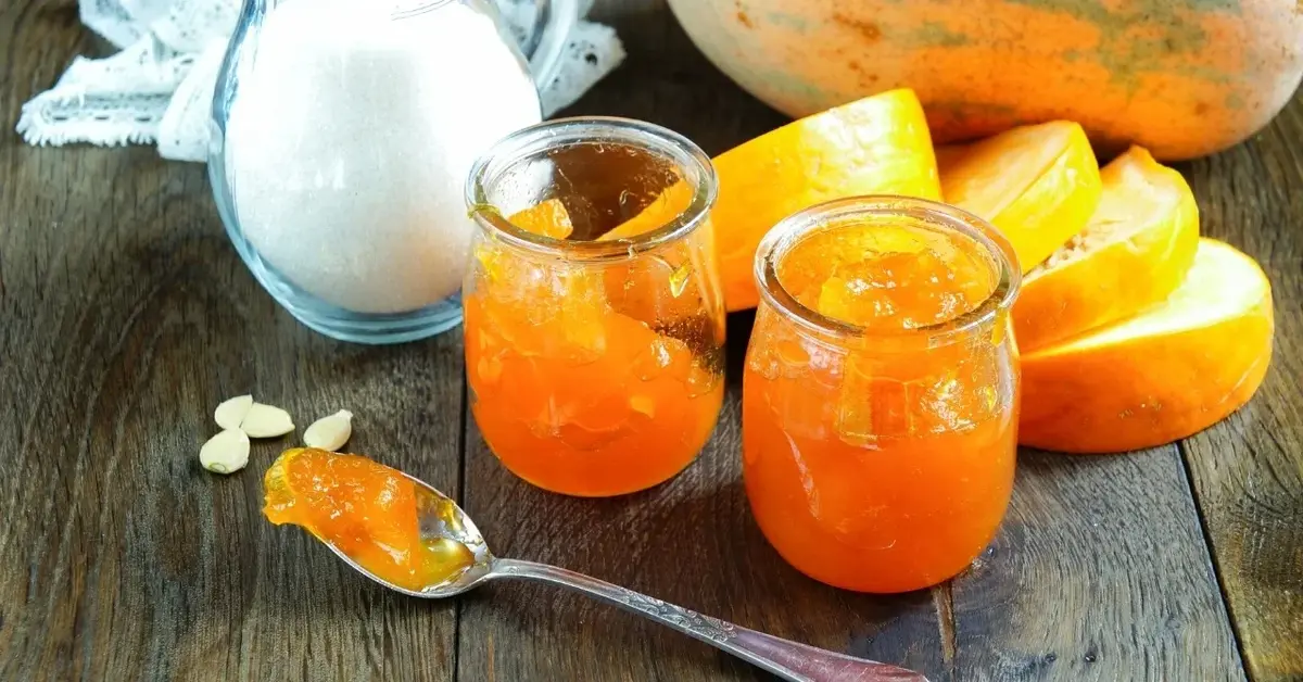 Dżem z dyni w dwóch słoiczkach, w tle pokrojone dynie i dodatki