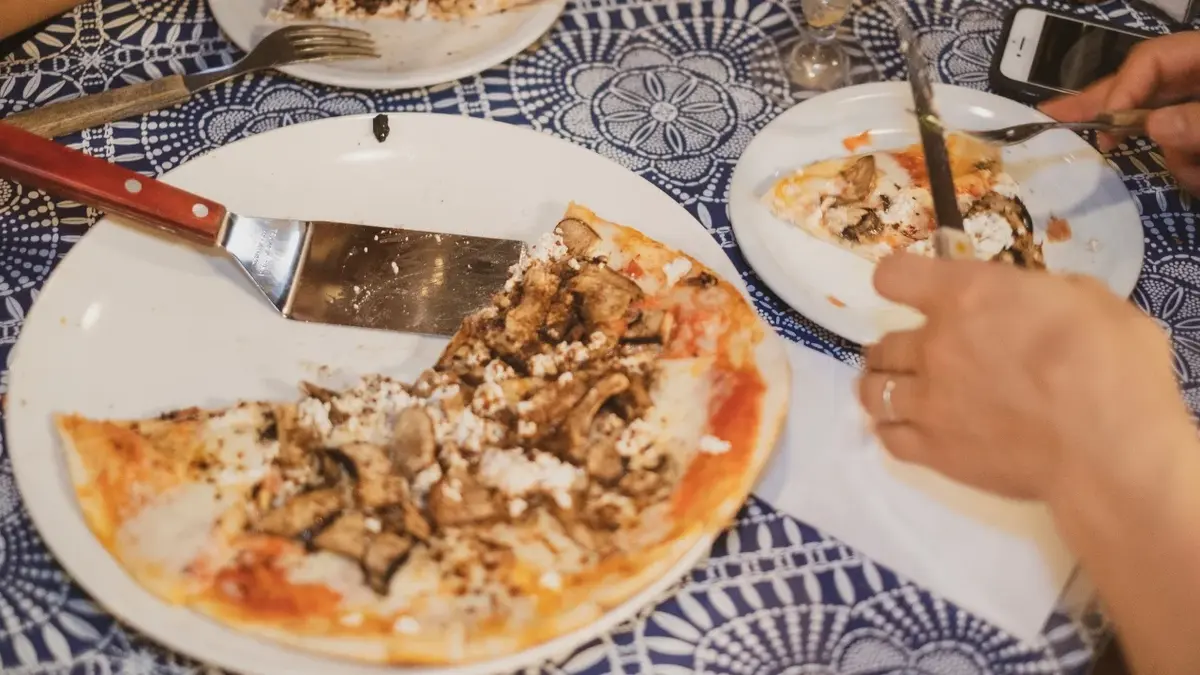 Pizza di funghi na dużym talerzu, obok na małym porcja pizzy