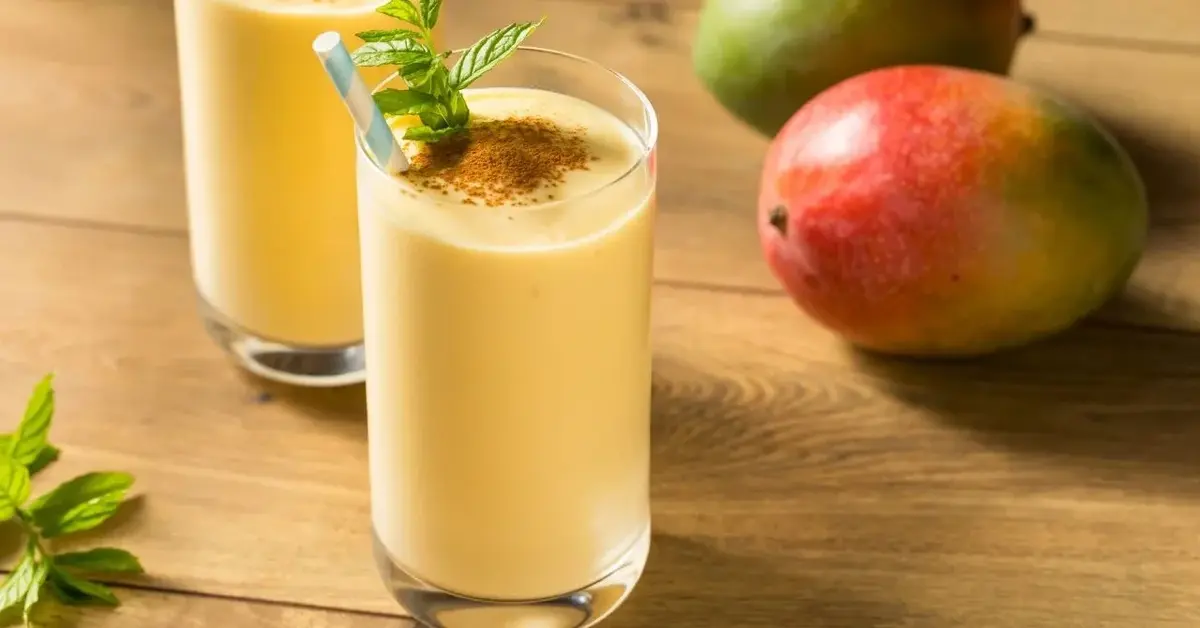 Mango lassi w szklankach, obok dojrzałe owoce mango