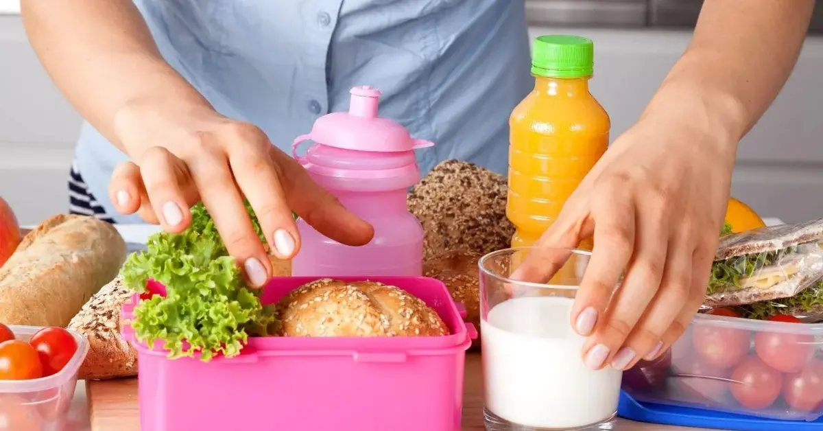 Kobieta pakująca śniadanie do szkoły do plastikowego pojemnika
