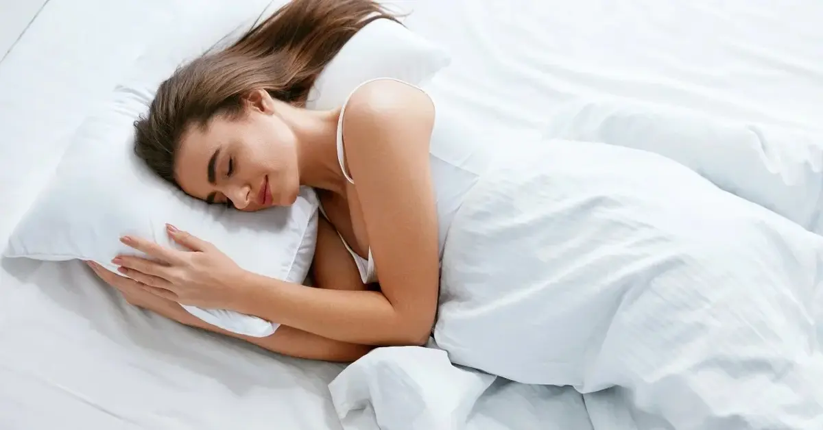 Kobieta śpiąca w białej pościeli 