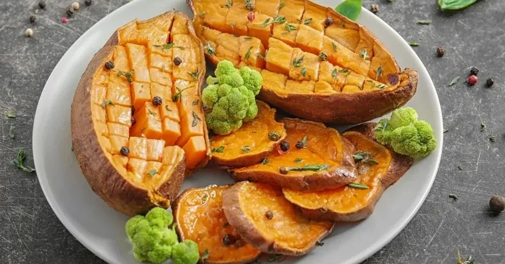 Pieczone bataty przekrojone na pół na białym talerzu