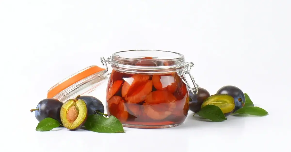 Śliwki w occie w słoiku, obok świeże śliwki