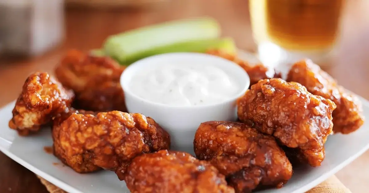 Skrzydełka Buffalo na talerzu  z sosem śmietankowym w miseczce