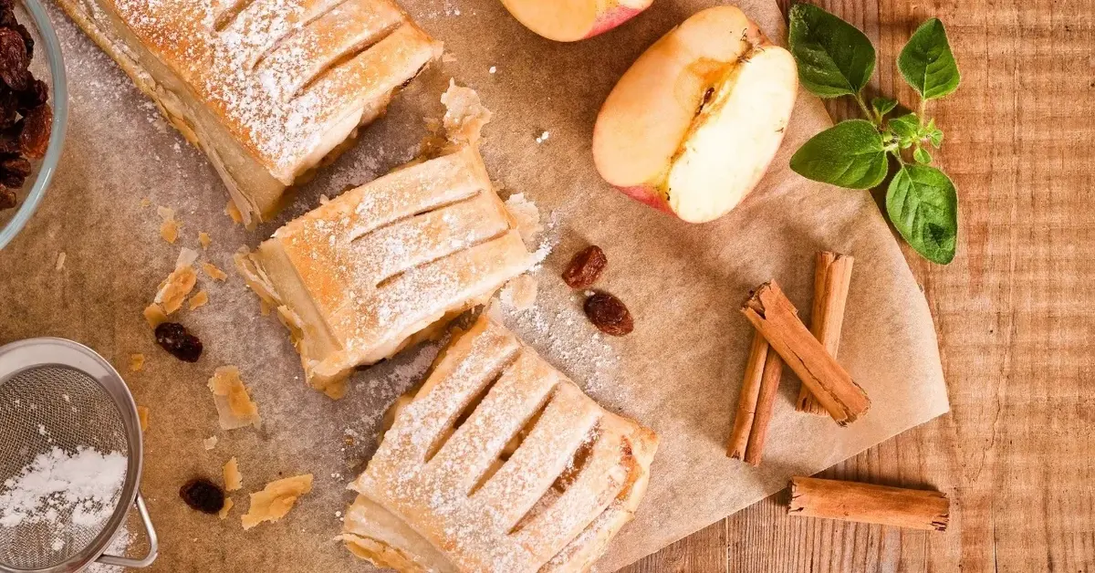 Strudel z ciasta francuskiego, obok jabłka i laski cynamonu