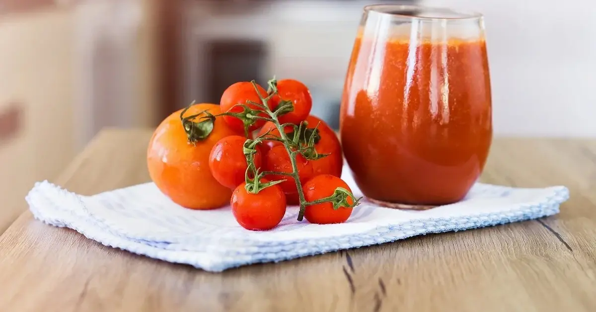 Sok pomidorowy  w szklance, obok pomidorki