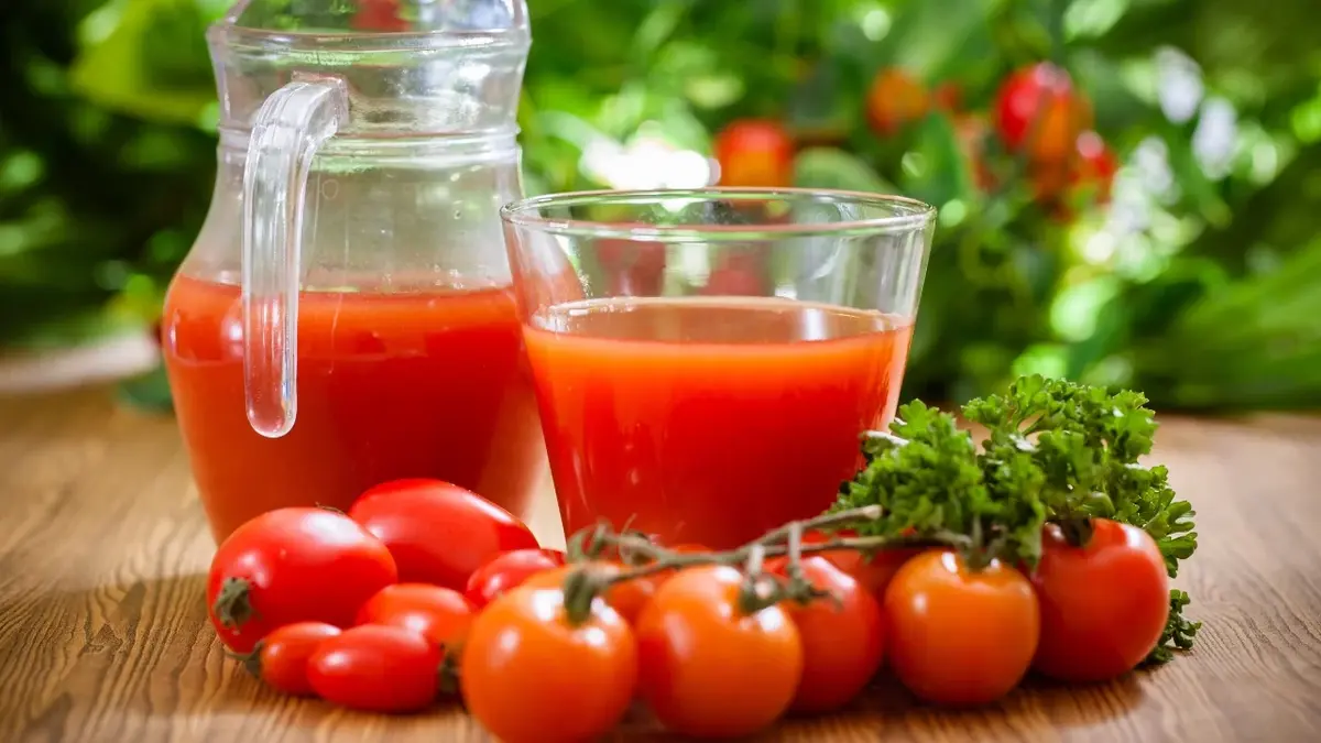 Sok pomidorowy  w szklance i dzbanku obok pomidorki