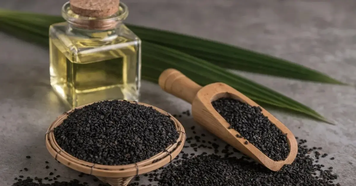 Olej z czarnuszki w buteleczce, obok nasiona czarnuszki