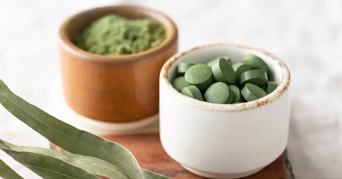Chlorella w proszku i tabletkach w małych miseczkach