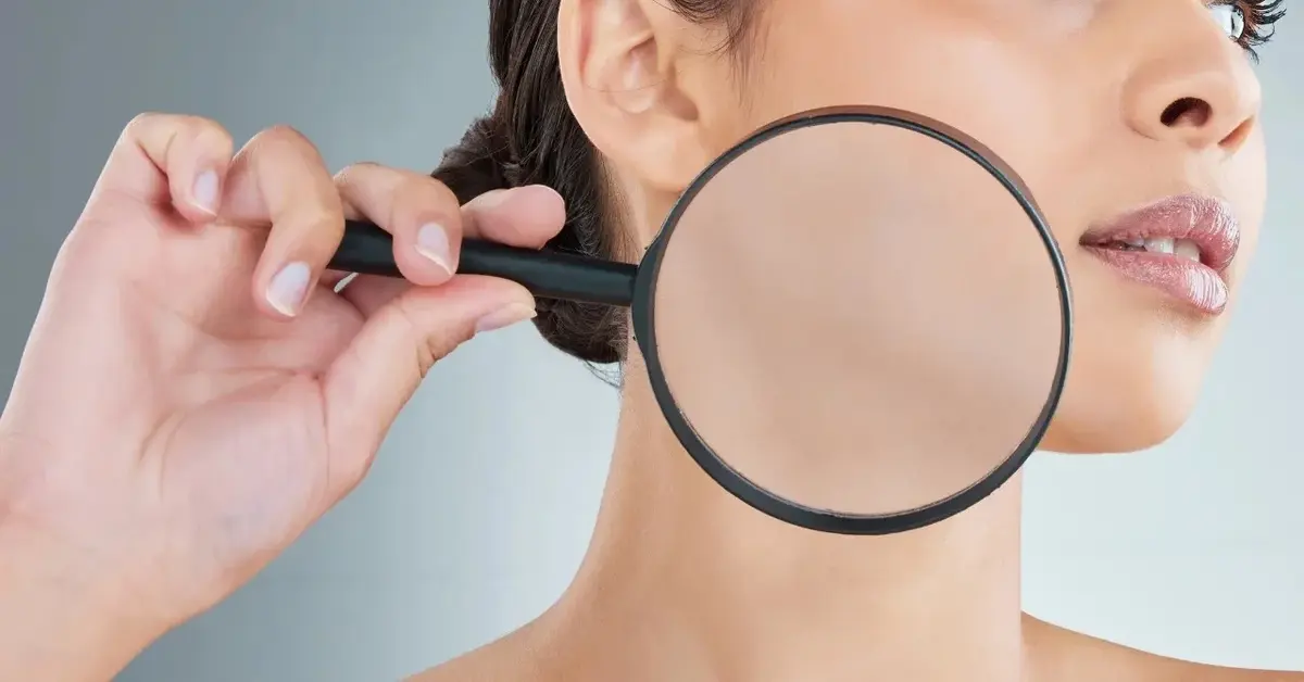 Twarz kobiety z lupą skierowaną na policzek