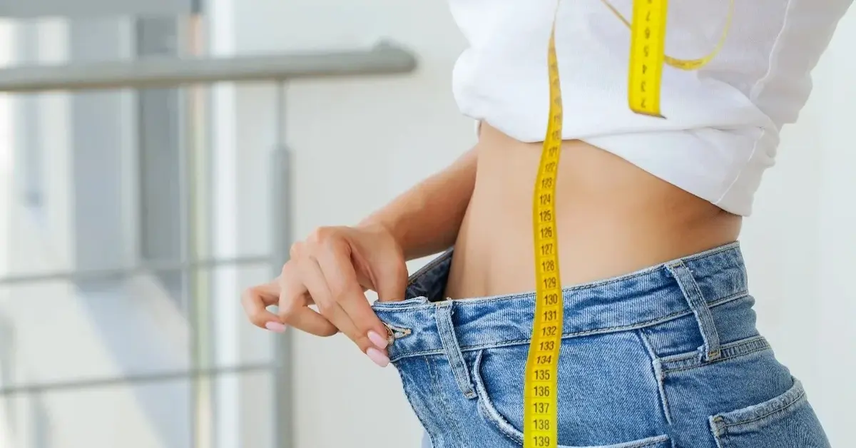 Kobieta w za dużych jeansach z miarką w ręce