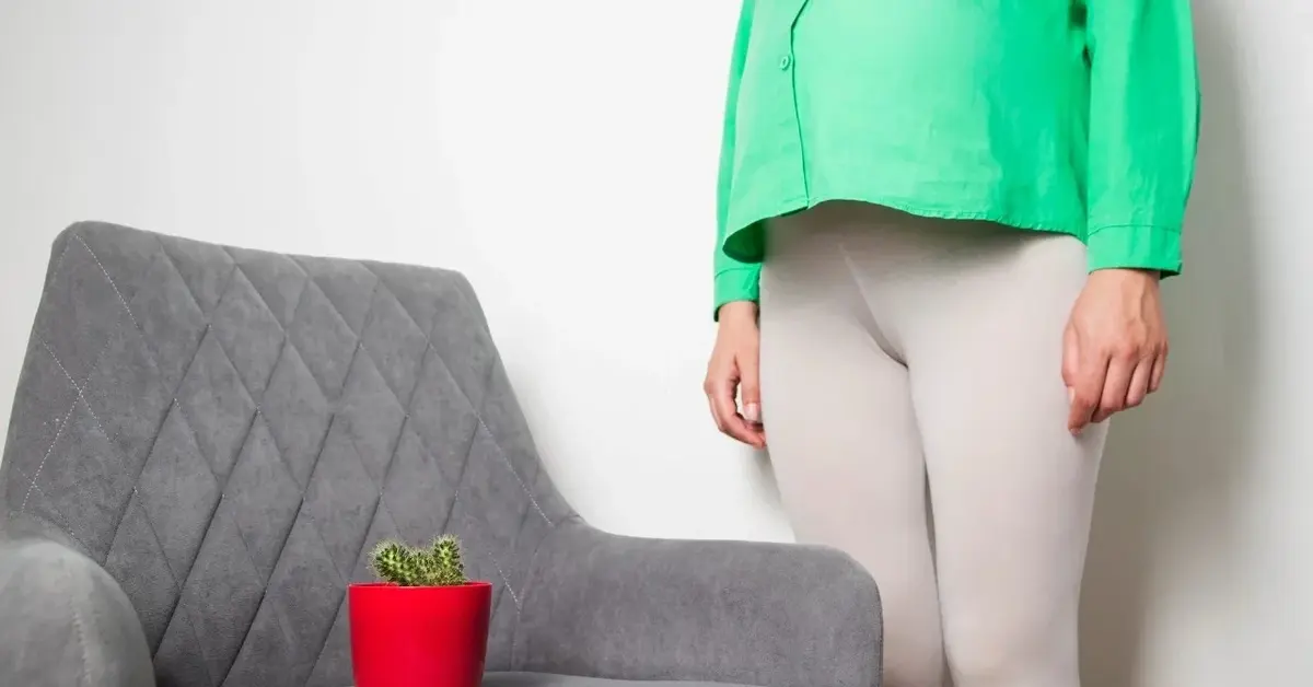 Kobieta w ciąży, obok fotel na którym stoi kaktus