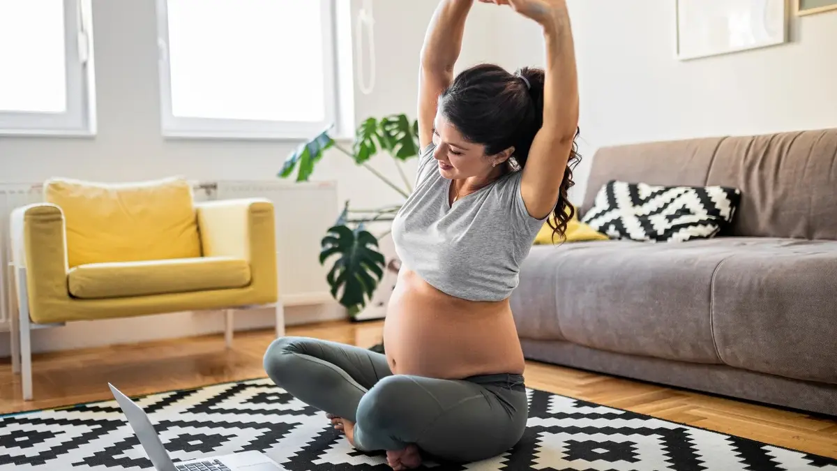 Kobieta w ciąży ćwicząca na podłodze w salonie