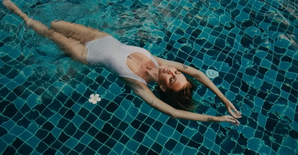 Kobieta w białym kostiumie pływająca na basenie na plecach